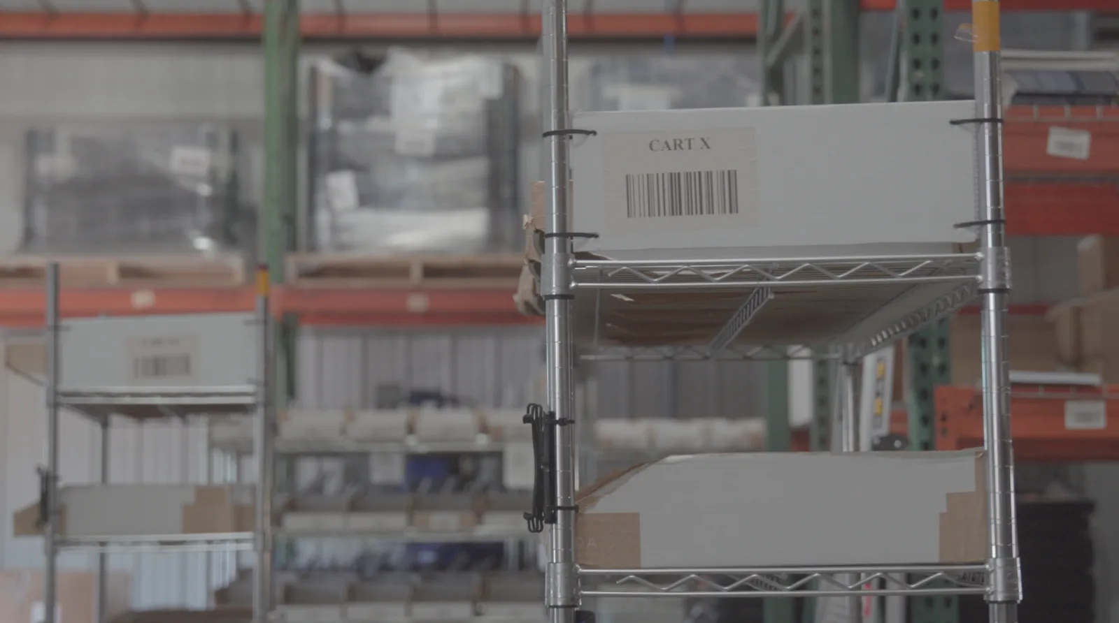 Still from Givington's warehouse b-roll: wire carts holding labeled boxes